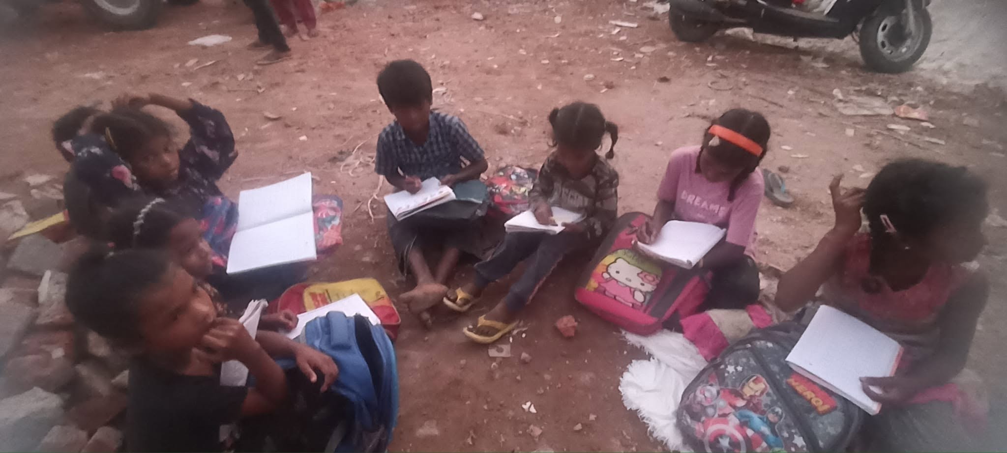Underprivileged children studying with books on the ground in Meerut
